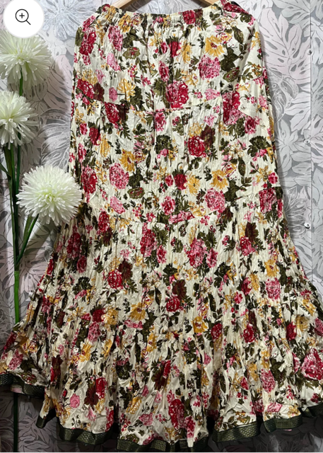 A white flora jaipuri skirt with a multicolored floral print, displayed on a mannequin against a patterned background.